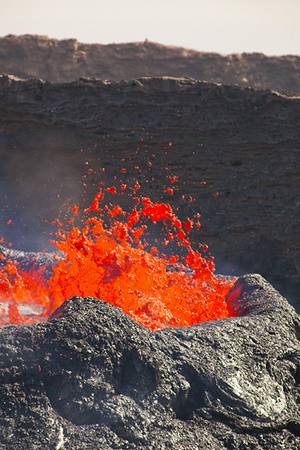 Magmatic gas escapes from the lava lake and creates spectacular fountains. The liquid lava is thrown many meters into the air, bursting into thousands of fragments. When liquid pieces are torn by the expanding escaping gas, lava is often torn into thin glassy threads, so-called Pele's hair. (Photo: Tom Pfeiffer)